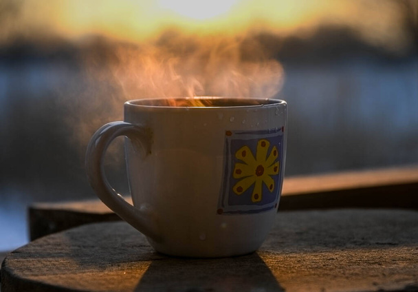 Morning cup of coffee on the winter terrace, against the backdrop of the rising sun. Sunrise. - Photo, Image