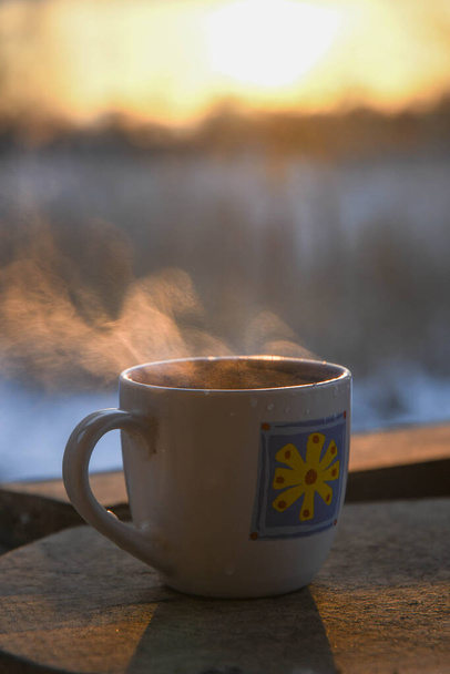 Morning cup of coffee on the winter terrace, against the backdrop of the rising sun. Sunrise. - Foto, Bild
