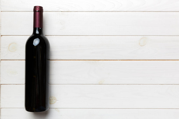 Jedna láhev červeného vína na barevném stole. Byt ležel, horní pohled the copy space. - Fotografie, Obrázek