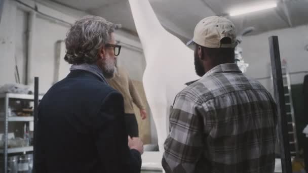 Diverse mannen bespreken giraffe standbeeld productie - Video