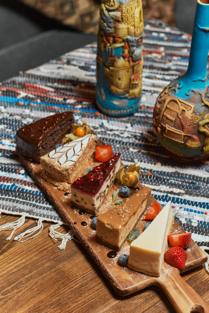Set of different cake slices on wooden table. - Fotoğraf, Görsel