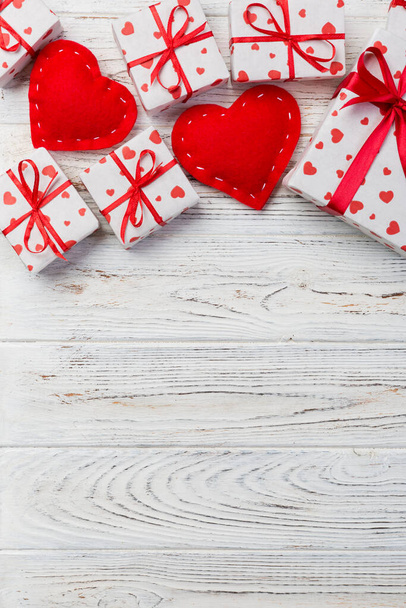 Valentin vagy más holiday kézzel jelen van papír, piros szívek és ajándék doboz a holiday wrapper. Jelenleg fehér fából készült asztallap Kilátás-val másol hely, üres hely a design ajándék doboz. - Fotó, kép