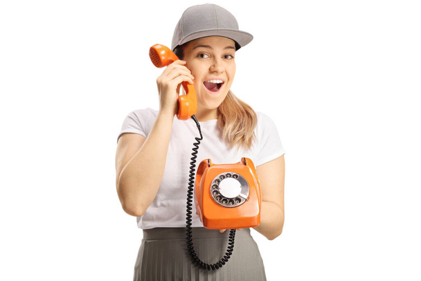 Cheerful young female holding an old vintage rotary phone isolated on white backgorund - Photo, Image