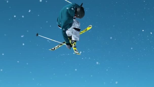 Sluiten omhoog: Skiër neemt een kicker en doet een draaiende greep met gekruiste ski 's. - Video