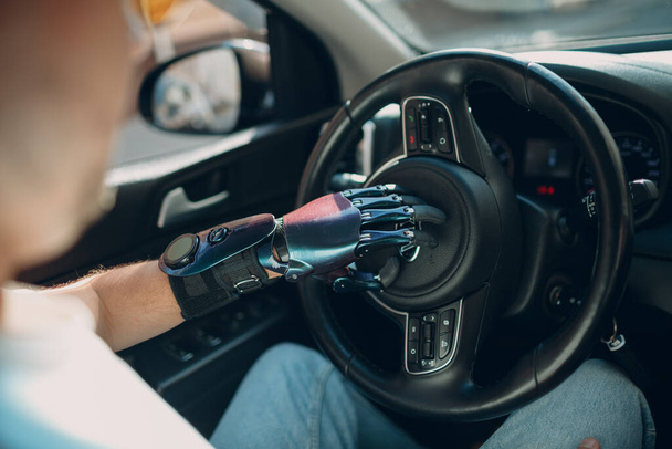 Jonge gehandicapte man bestuurder met kunstmatige prothetische hand rijden auto. - Foto, afbeelding