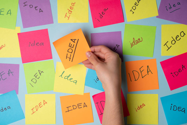 Bright new idea. Creative person brainstorming while writing original thoughts and ideas on colorful sticky notes - Photo, image