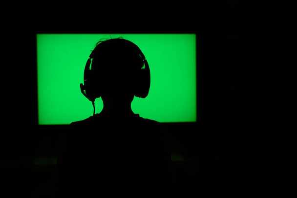 Dospívající s sluchátky za neonově zelené televizní obrazovce - Fotografie, Obrázek