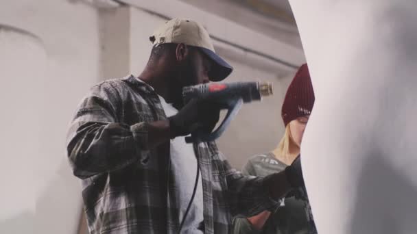 Artesanos multirraciales pintando escultura juntos - Metraje, vídeo