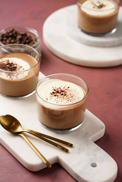 Italiaanse chocolade en koffie mousse dessert semifreddo - half bevroren ijs met slagroom en cacaopoeder in kleine glazen op paarse ondergrond - Foto, afbeelding