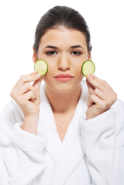 Beautiful woman receiving facial mask of cucumber - Фото, изображение
