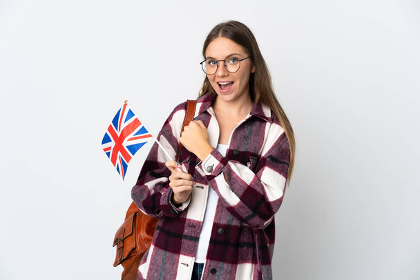 Jonge Litouwse vrouw met een vlag van het Verenigd Koninkrijk geïsoleerd op witte achtergrond die een overwinning viert - Foto, afbeelding