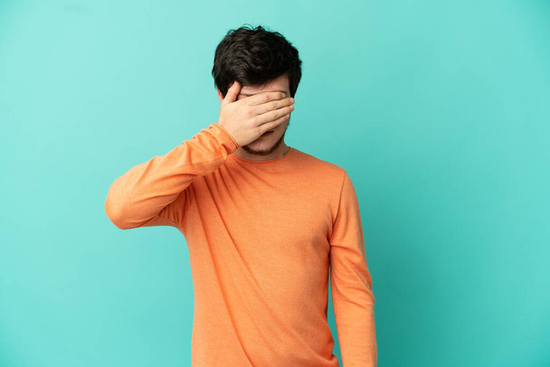 Young Russian man isolated on blue background covering eyes by hands. Do not want to see something - Fotó, kép