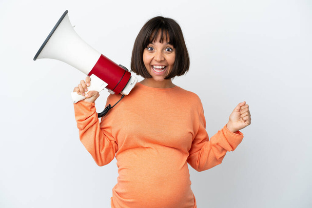 Молодая смешанная раса беременная женщина изолирована на белом фоне крича через мегафон и указывая на сторону - Фото, изображение
