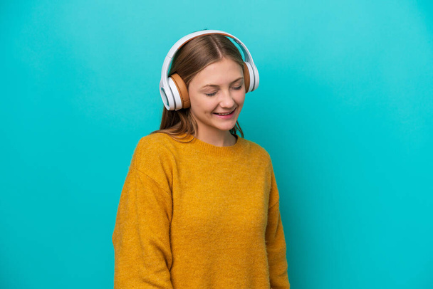 Fiatal orosz nő elszigetelt kék háttér hallgat zenét - Fotó, kép