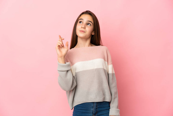 Little girl isolated on pink background with fingers crossing and wishing the best - Фото, зображення