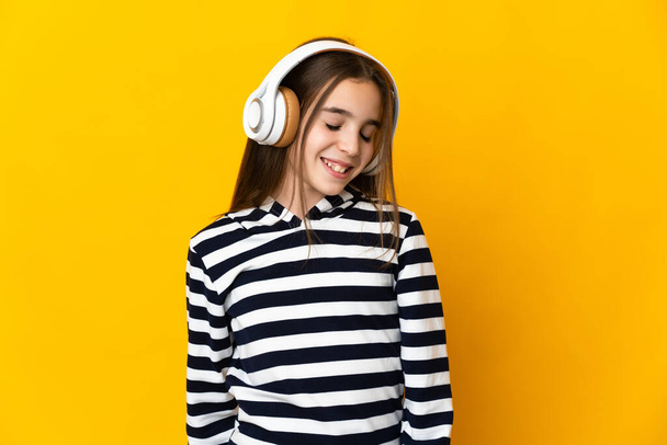 Menina isolada no fundo amarelo ouvindo música - Foto, Imagem