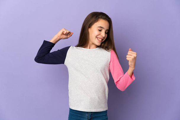 Little girl isolated on purple background celebrating a victory - Photo, Image