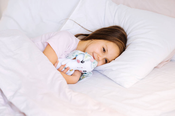 маленькая девочка с игрушкой спит дома - Фото, изображение