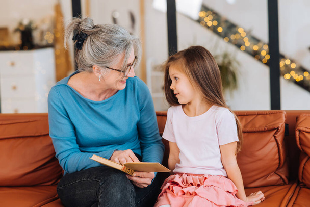 Гарна літня жінка бабуся читає історію онуці
. - Фото, зображення