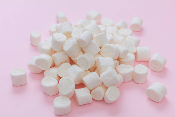 Marshmallows heap on pastel pink background. White fluffy mini dessert, sweet kids birthday party snack, closeup view - Photo, Image