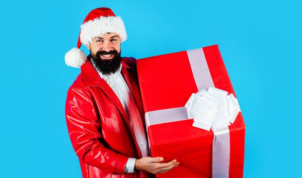 Smiling man in Santa hat with big gift box. New year present. Christmas holiday. Delivery gifts. - Valokuva, kuva