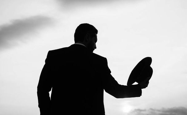 businessman man silhouette with hat against sunset sky, fashion - 写真・画像