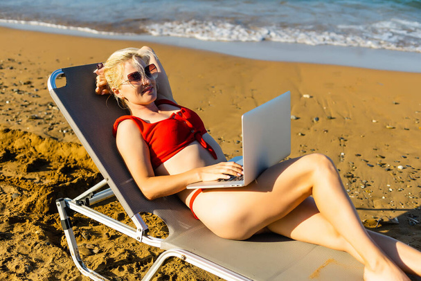 жінка використовує ноутбук на пляжі
 - Фото, зображення