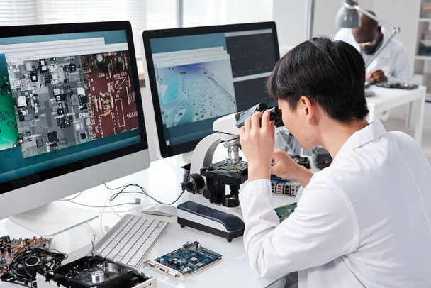 Joven investigadora asiática mirando al microscopio - Foto, Imagen