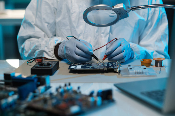 Gloved technician or repairman soldering details of motherboard with tweezers - Foto, Imagen