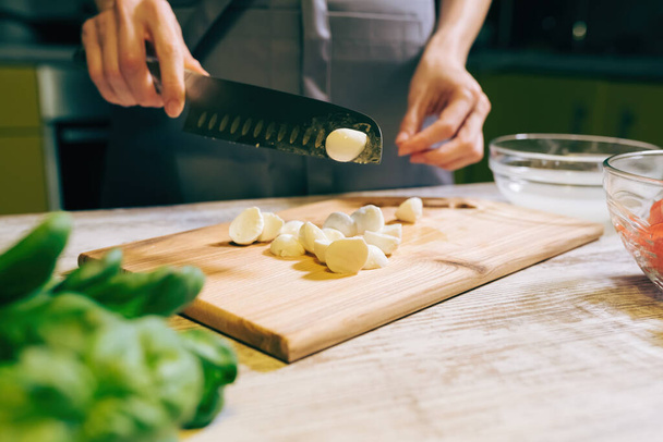 Cutting cheese Mozzarella for cooking salad at kitchen, prepare healthy meal - 写真・画像