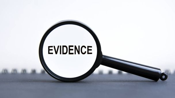глядя через увеличительное стекло на слово Evidence, бизнес-концепцию. лупа на белом фоне - Фото, изображение