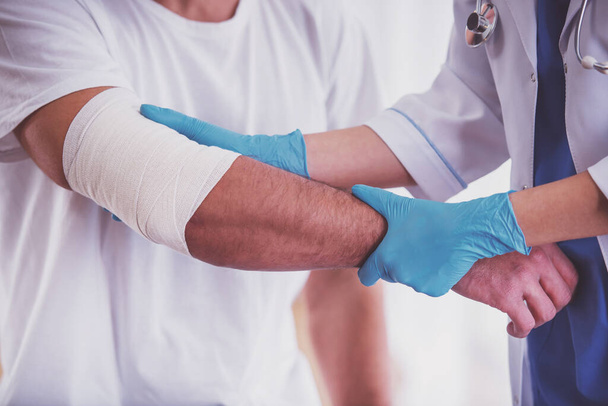 Verletzungen an den Händen. junger Mann mit verletzten Händen. junge Ärztin hilft der Patientin - Foto, Bild