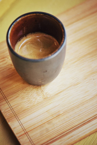 Hot espresso coffee in a small cup, placed on a wooden tray  in retro coffee shop. - Photo, Image