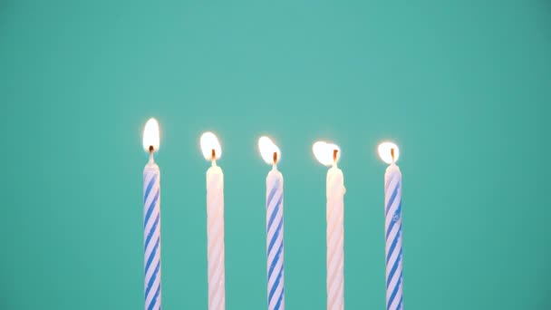 Concepto de Feliz Cumpleaños Hecho de Velas de colores ardientes sobre fondo azul o turquesa. Quemando velas de cumpleaños de cinco años. Vídeo de resolución 4K - Metraje, vídeo