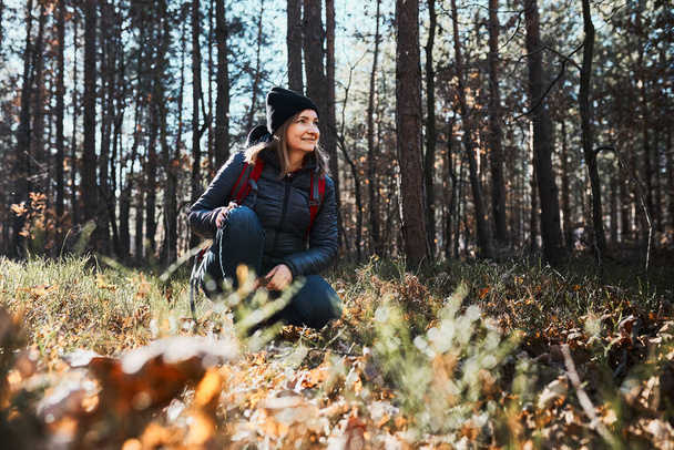 Woman enjoying hike on sunny vacation day. Female with backpack walking through forest path. Spending summer vacation close to nature - Foto, afbeelding