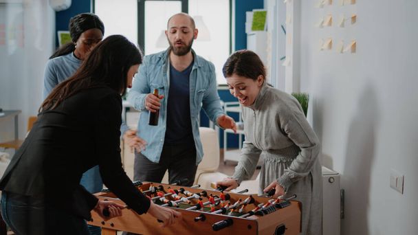 Colleagues playing foosball game and woman winning - Photo, Image