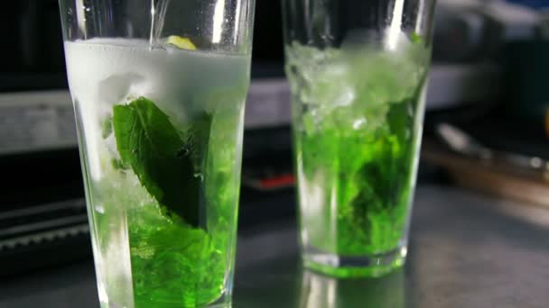 barman leje lemoniadę do szklanki z lodem, cytryna, mięta i syrop - Materiał filmowy, wideo