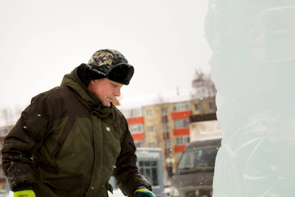 Portrait facial d'un travailleur coiffé d'un chapeau avec des boucles d'oreilles occupées par l'aménagement de la ville de glace - Photo, image