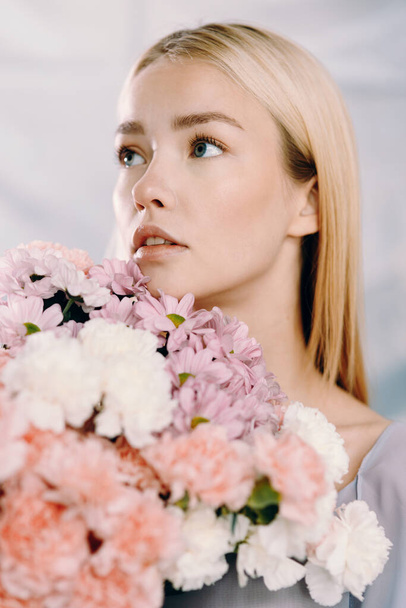 Portrait of a young beautiful woman with white and pink flowers. Spring fashion photography, with polyethylene. - Valokuva, kuva