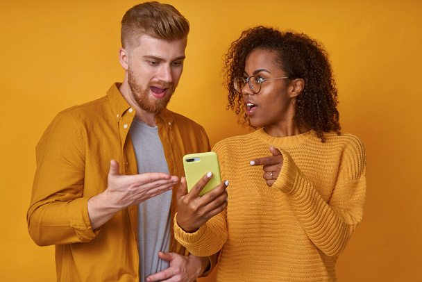 Multiethnic Caucasian man and African American woman stand with phone - Foto, Bild