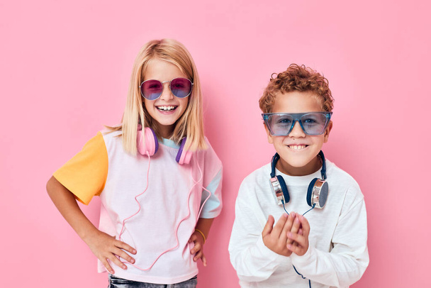 Porträt eines Mädchens und eines Jungen mit Kopfhörern posiert rosa Hintergrund - Foto, Bild