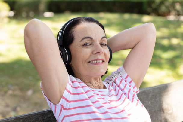 portrait of senior woman at the park listening to music - Foto, imagen