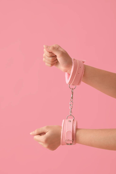 Young woman in handcuffs from sex shop on color background - Zdjęcie, obraz