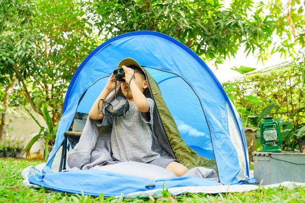 happy boy in camping tent.boy holding binoculars in adventure time.soft focus. - Zdjęcie, obraz