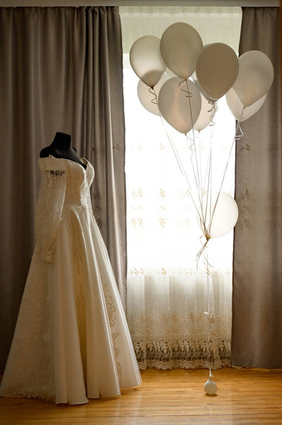 φόρεμα της νύφης σε ένα μαύρο μανεκέν, μπαλόνια γύρω, το γάλα χρώματος φόρεμα. - Φωτογραφία, εικόνα
