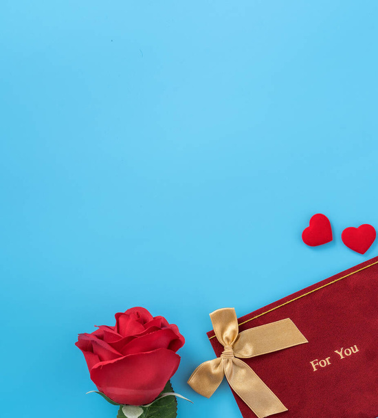 Red greeting card with golden bow at Valentine's day, anniversary, mother's day and birthday for a surprise on blue background, copy space, top view - Φωτογραφία, εικόνα