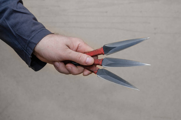 Una mano con tres cuchillos. Varón adulto sosteniendo cuchillos. Vista lateral - Foto, imagen
