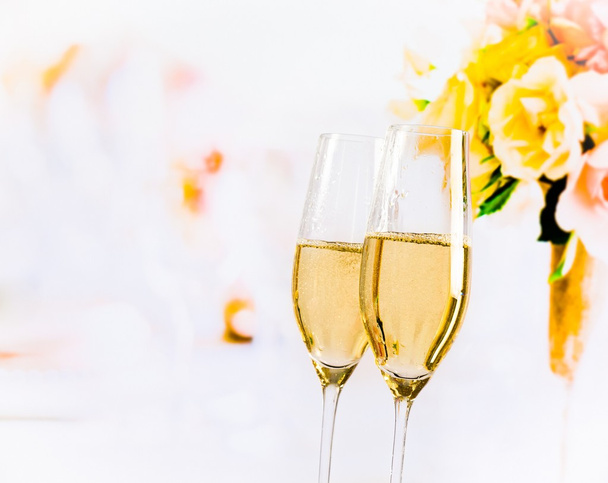 champagne flutes with golden bubbles on wedding flowers background - Photo, Image