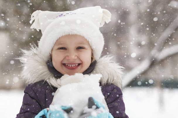 Winter active holidays in snowy park. Winter child face. Happy girl is smiling. Winter joyful portrait. - Foto, afbeelding