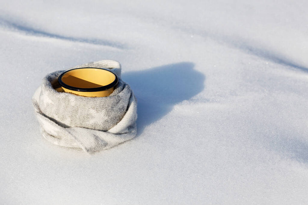 Bevanda calda in inverno. Tazza con bere caffè o tè avvolto in sciarpa di lana su sfondo bianco neve - Foto, immagini